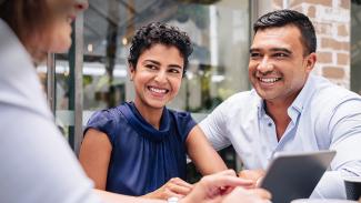 Three people sitting at a table smiling at each other