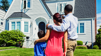 Family standing in front of a house and gazing at it
